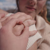 A short video showing a close-up of a hand wearing a delicate gold ring with a single row of baguette and round cut clear gemstones in a morse code pattern.