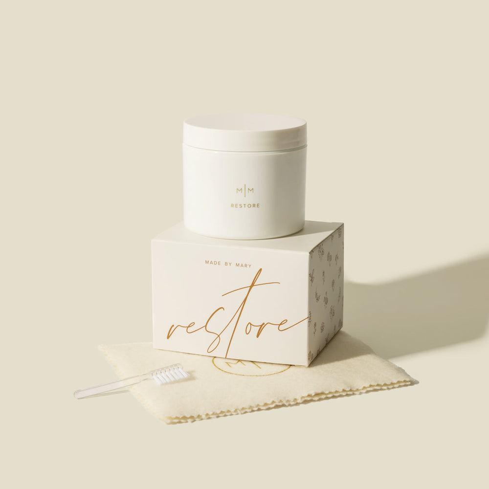 Restore jewelry cleaner jar and box with a small cleaning brush on a cream cloth.