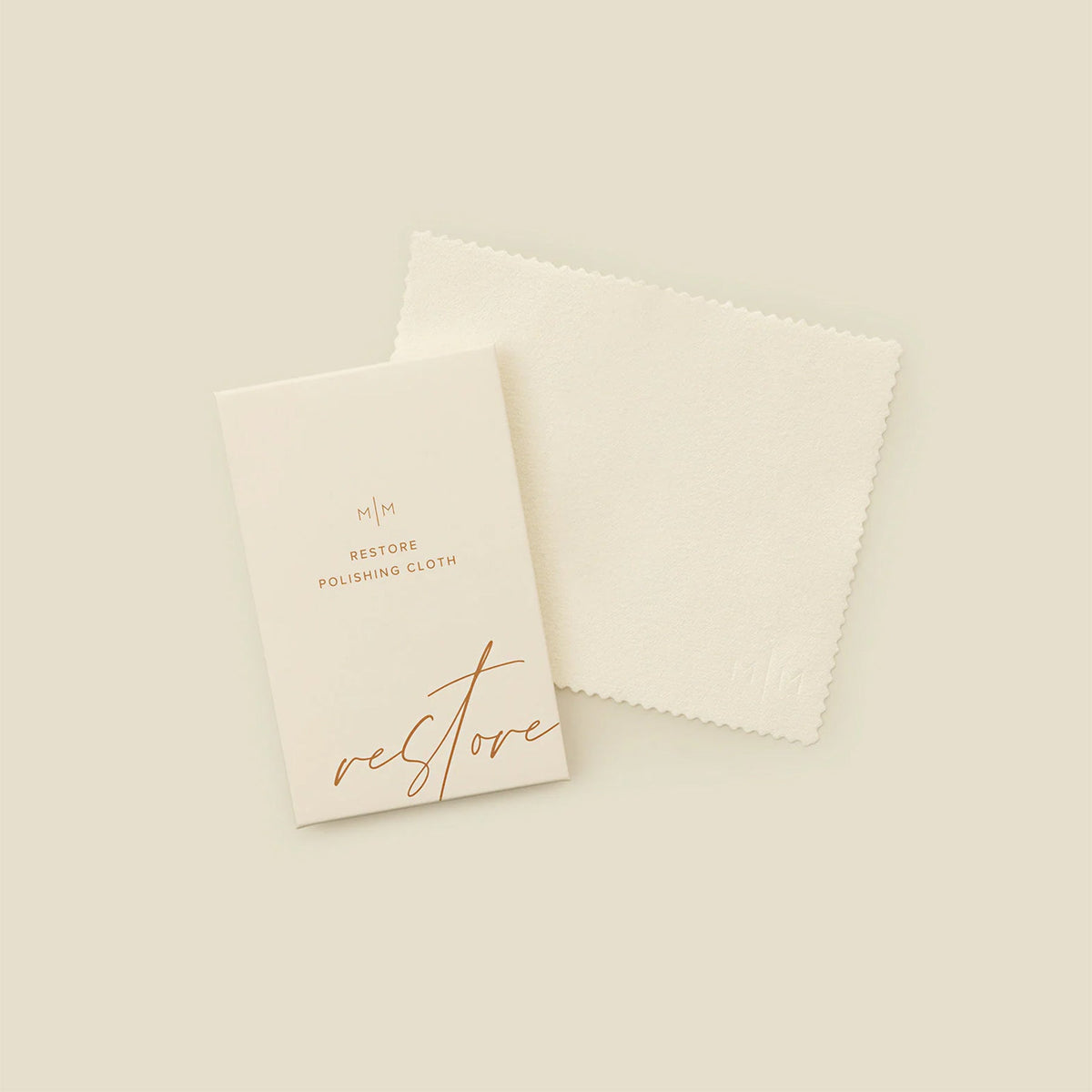 A square cream polishing cloth with a rectangular card on top with the words 'RESTORE POLISHING CLOTH', shown on a solid light beige surface.