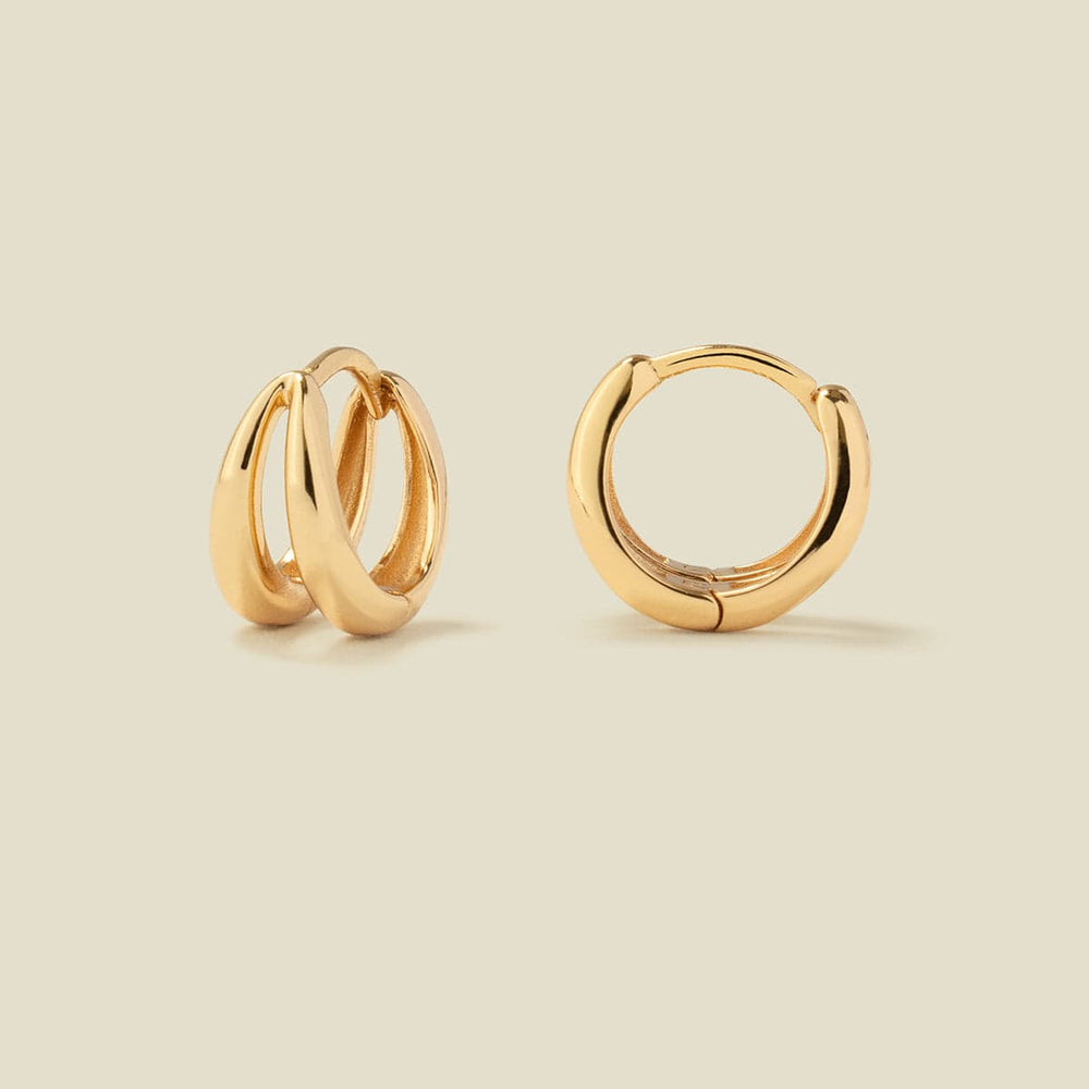 Two polished gold huggie hoop earrings made up of two stationary separate hoops attached at the earring post, shown on a warm beige background, with one earring facing forward and the other angled to show the side profile.
