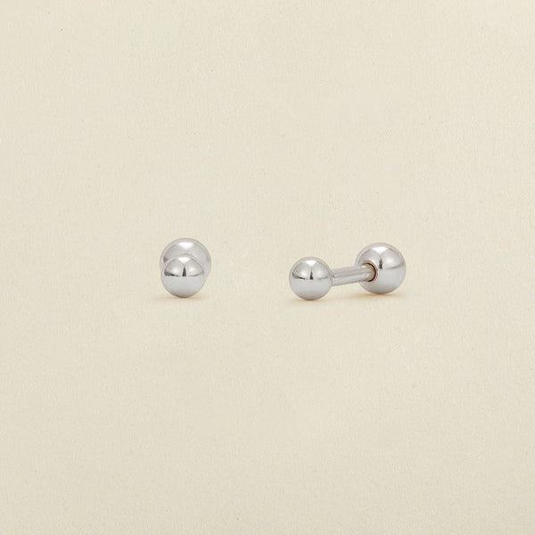 A pair of silver round bead studs with round ball backings, shown on a solid light beige background.