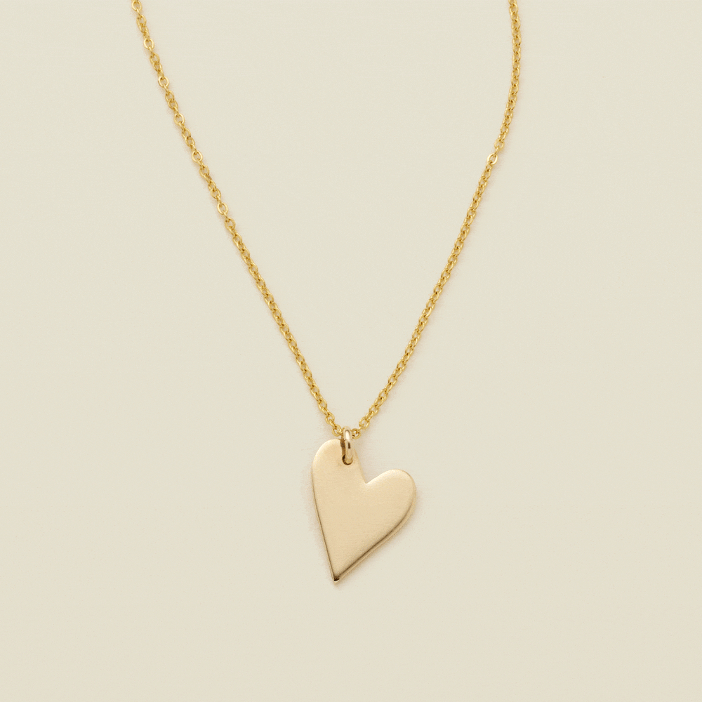 A gif of a delicate gold pendant chain necklace with a flat gold heart charm, starting blank then being engraved with the letter 'M'. From there, multiple smaller engraved heart charms are added one by one, each with a different initial.